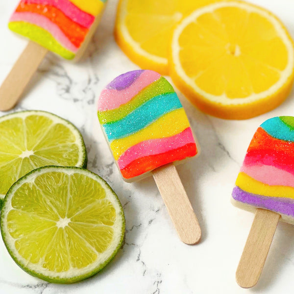 fantasy rainbow glitter candy marzipan popsicles next to fruit closeup