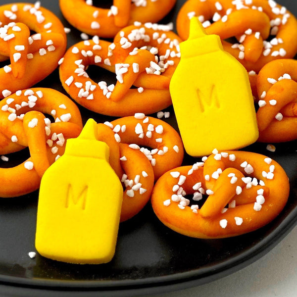 marzipan pretzels and mustard on  a black plate