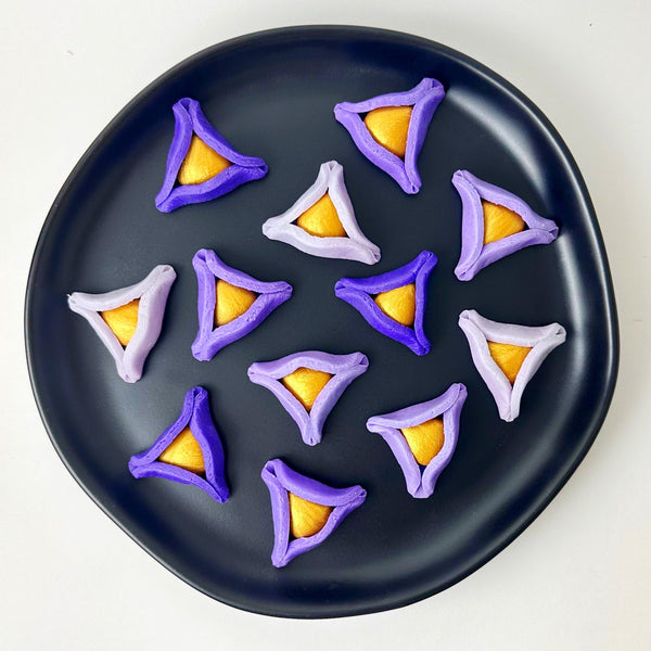 purple ombré marzipan hamamtaschen on a black plate