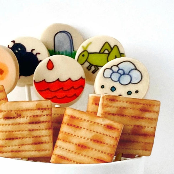 Passover Seder super set with many apples and ten plagues with frogs marzipan candy lollipops close upPassover Seder candy matzah ten plagues with frogs marzipan lollipops close up