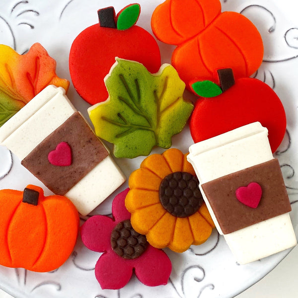 Autumn collection with pumpkins, coffee cups, flowers, maple leaves and apples marzipan candy tiles close up