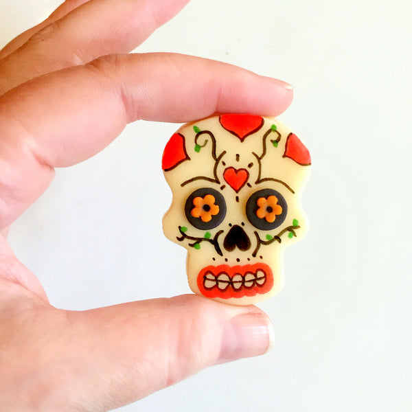 hand holding red Halloween Day of the Dead modern sugar skull marzipan candy tile